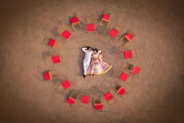 A creative drone shot of a couple from above, capturing their unique pose and surroundings, taken by Fotographiya